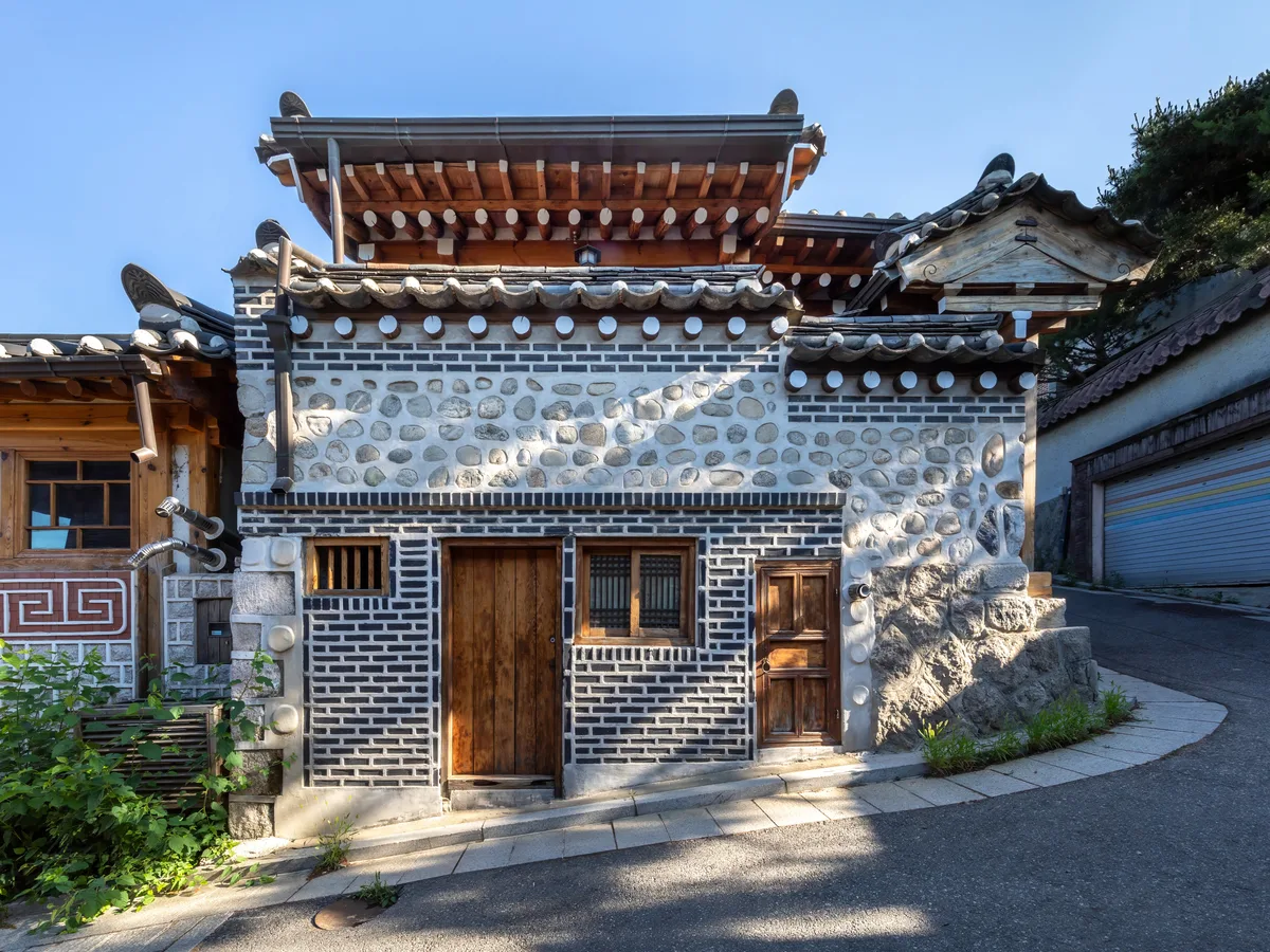 Traditional hanok house with wooden doors along a steeply sloping street in Bukchon Hanok Village, Seoul