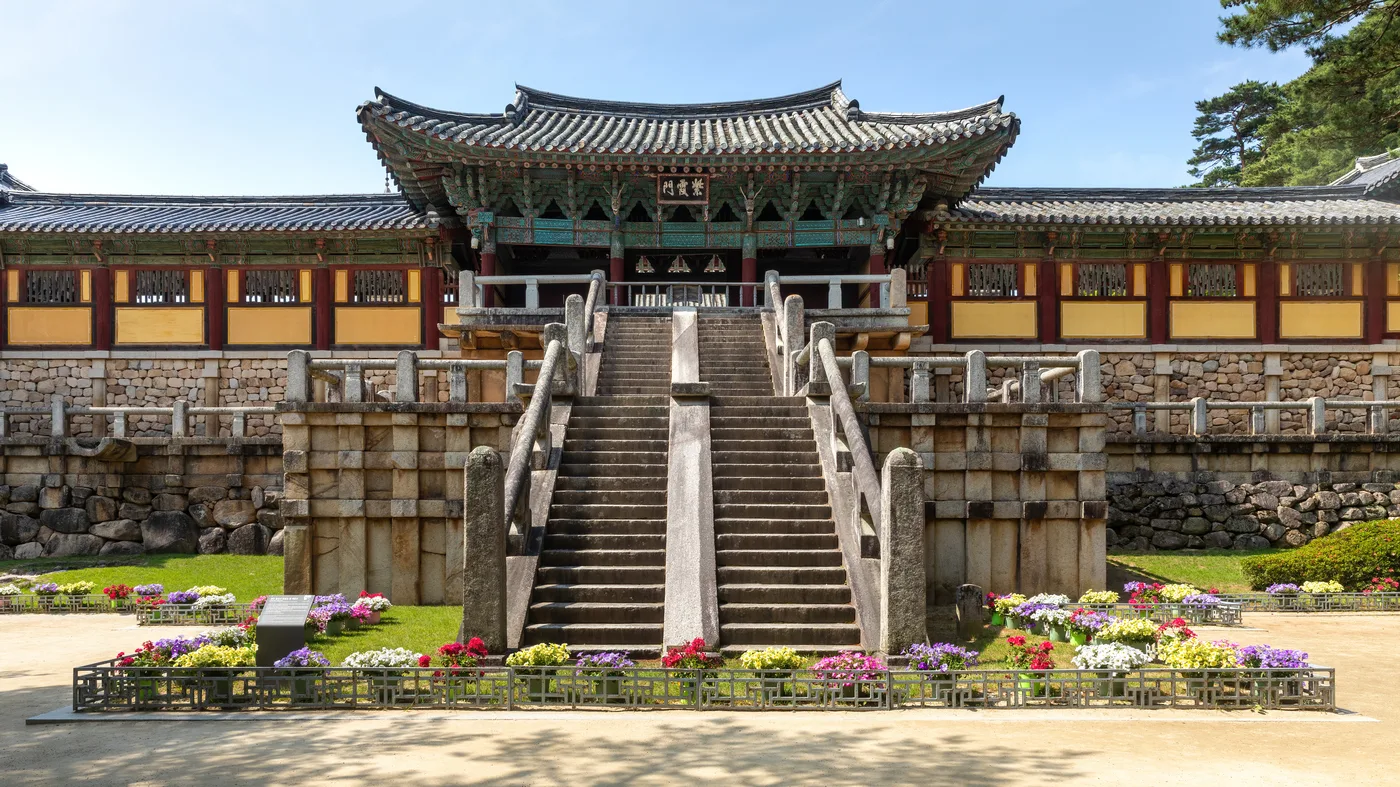 Stone staircase leading up to the entrance gate of Bulguksa Temple in Gyeongju, flanked by colorful flower beds