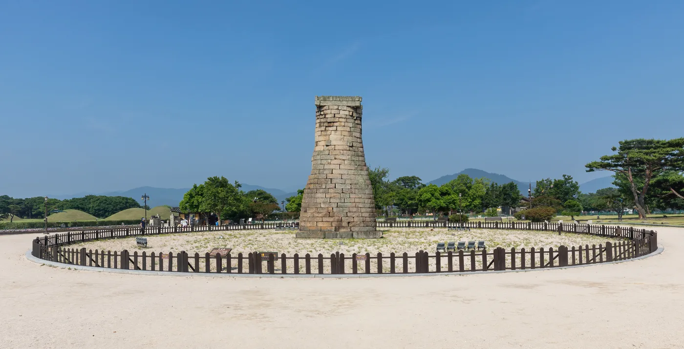Cheomseongdae, a stone astronomical observatory tower from the Silla dynasty, standing in a grassy field under blue sky in Gyeongju