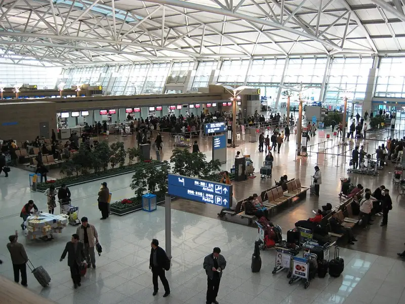 Check-in lobby at Incheon International Airport with travelers and luggage before departure