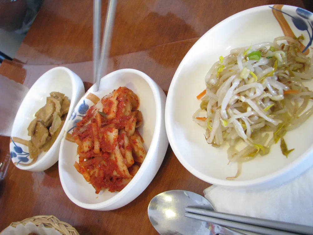 Korean banchan side dishes Korean banchan side dishes including kimchi, seasoned bean sprouts, and braised vegetables, with chopsticks resting on a plate