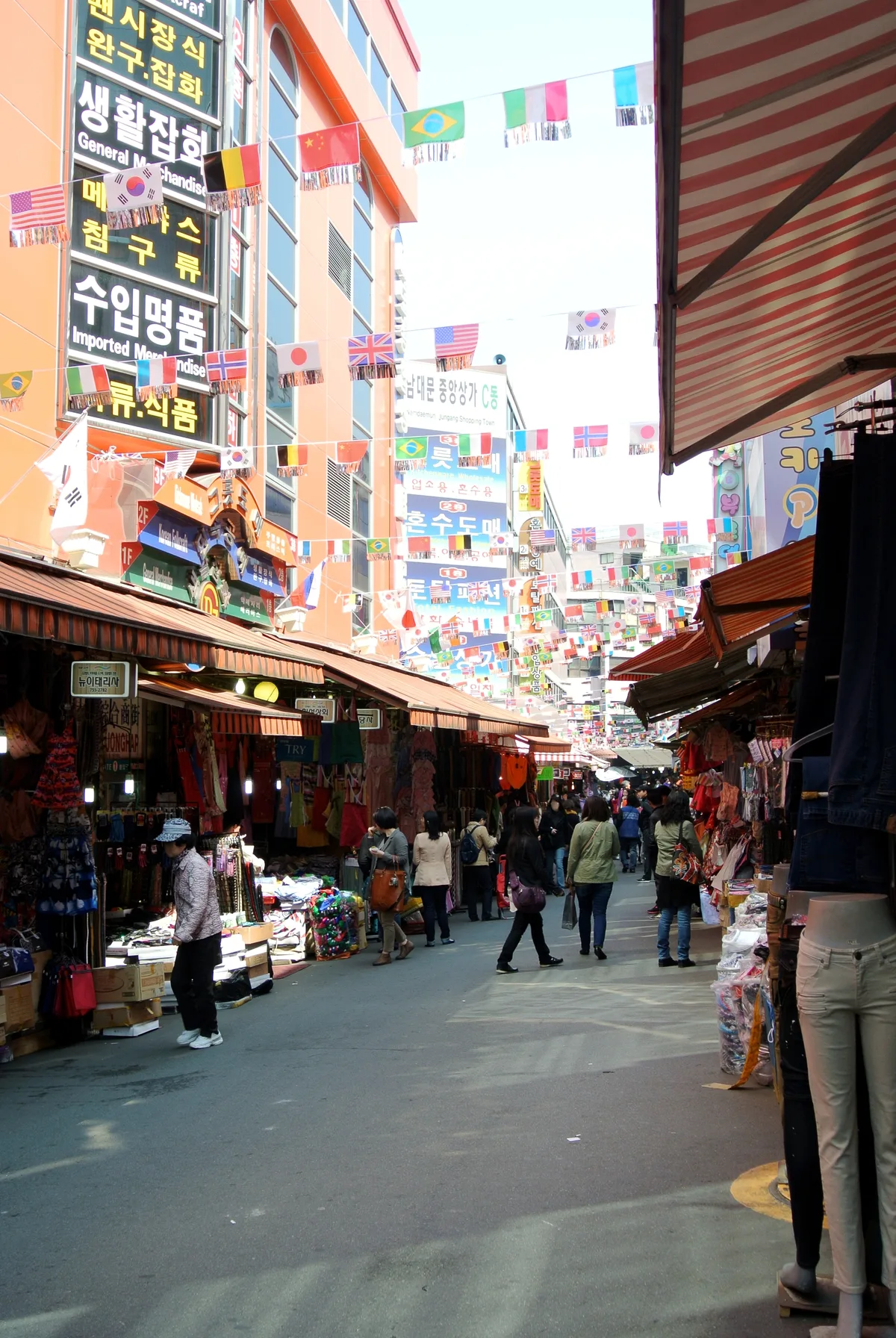 A Namdaemun Market Alley A busy alley in Namdaemun Market, Seoul, lined with clothing stalls and hung with international flags overhead