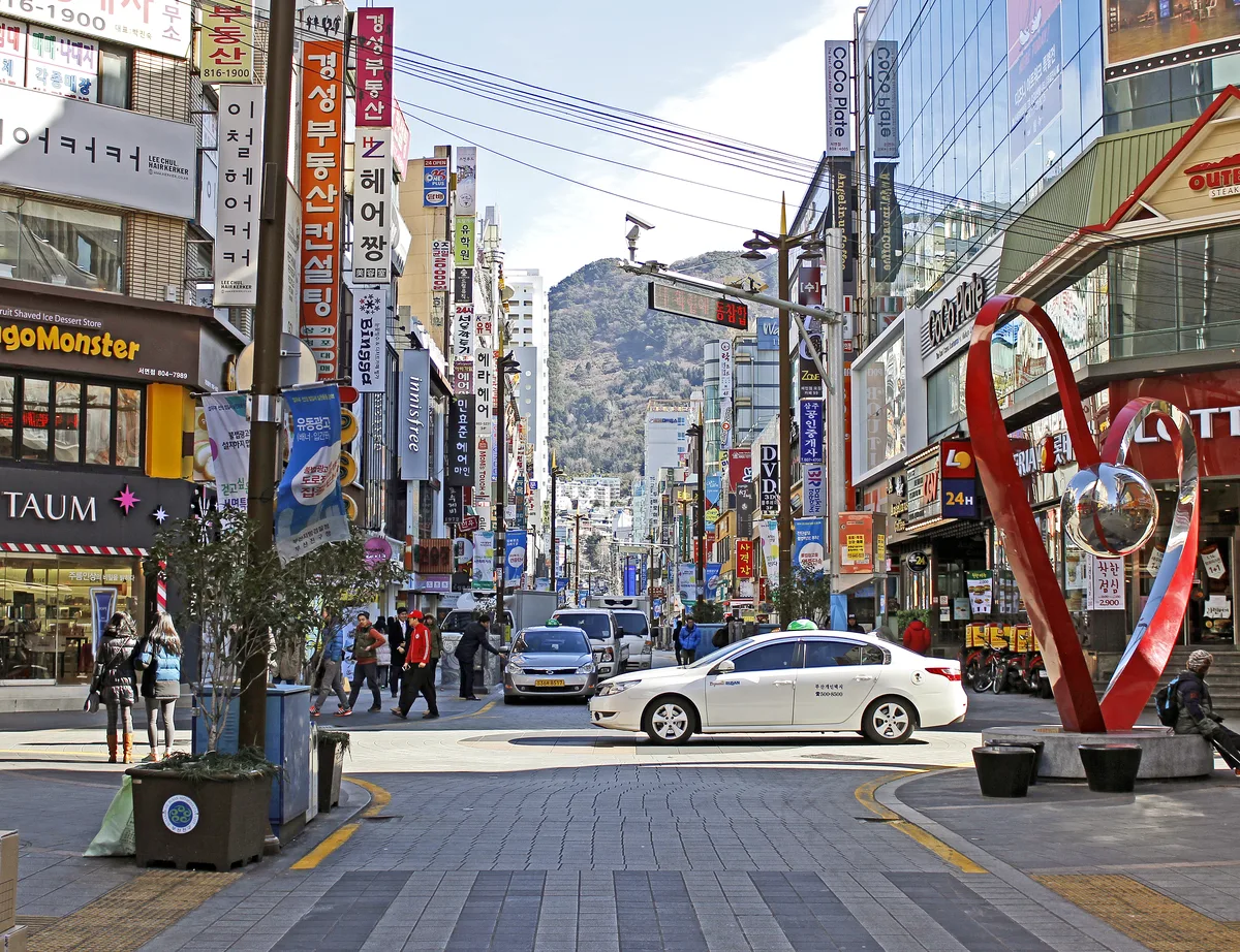 Busy shopping street in Seomyeon, Busan, lined with signage for cosmetics shops, cafes, and restaurants