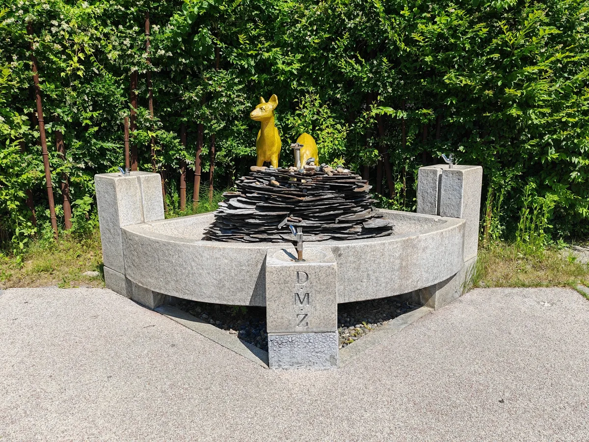 Stone monument with a golden deer statue and stacked slate, marked DMZ, near the entrance to the Third Tunnel of Aggression